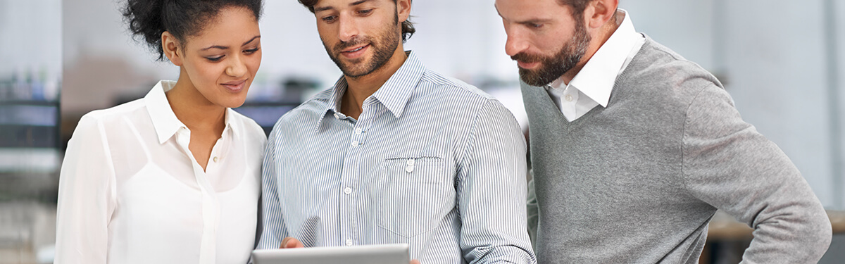 three co-workers viewing image on a tablet